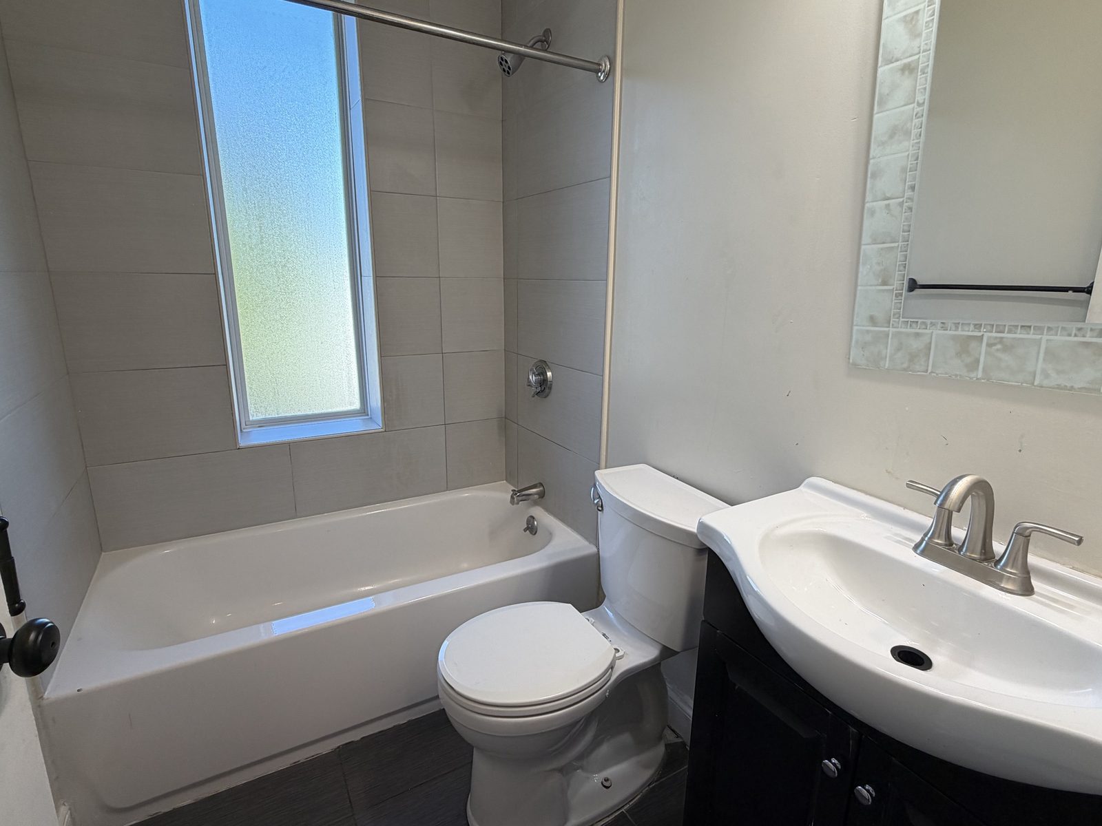 Bathroom with tub, tiled shower wall and vanity