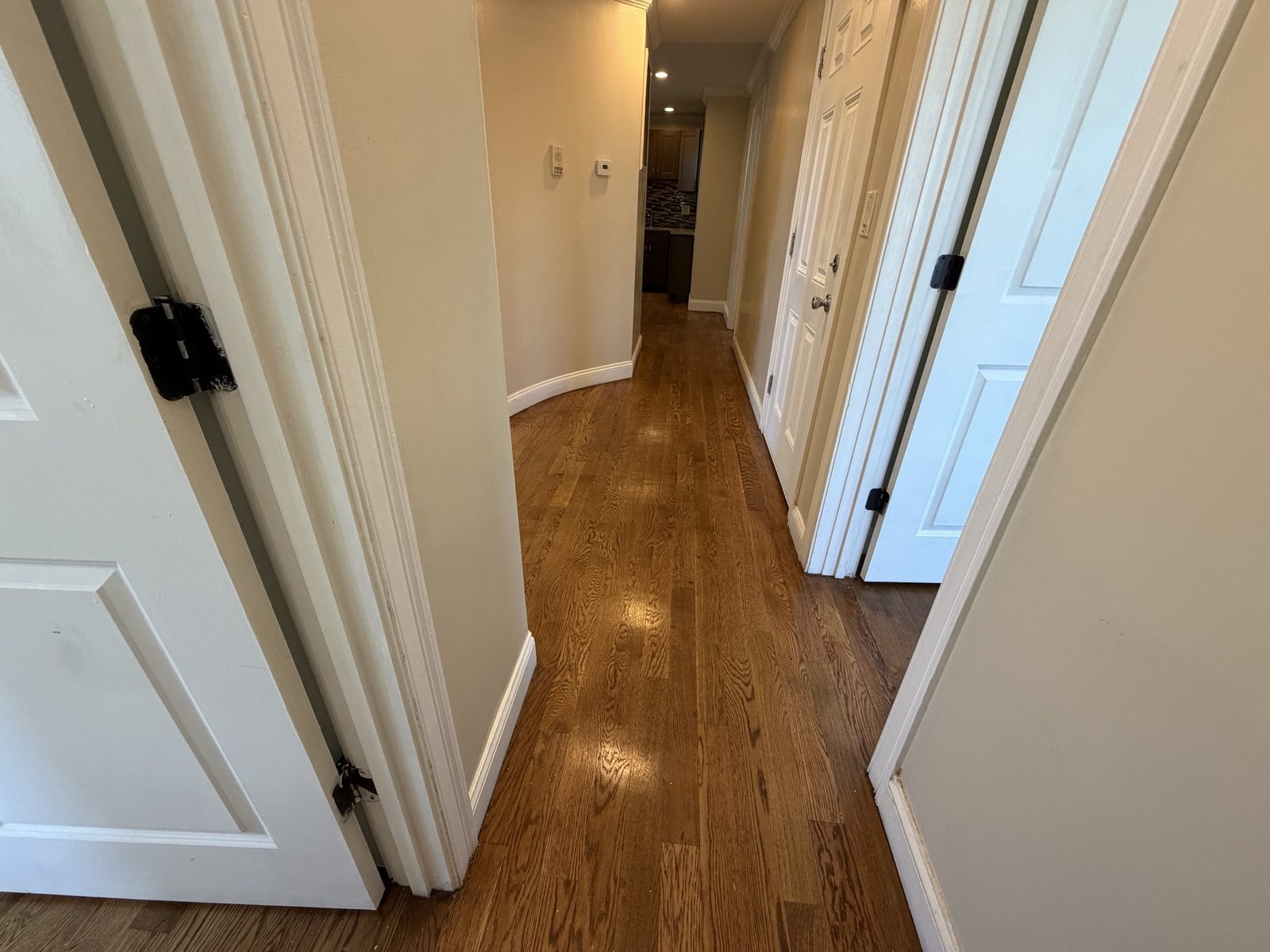 Hallway with hardwood floors leading to the kitchen