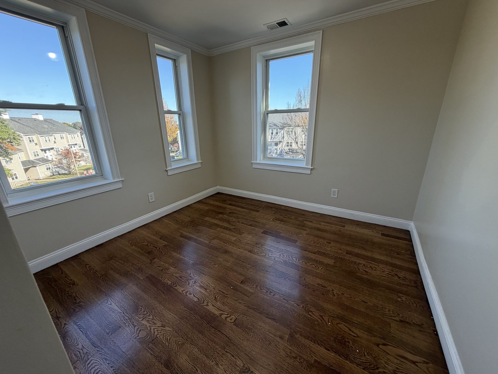 Room with three windows and hardwood floors