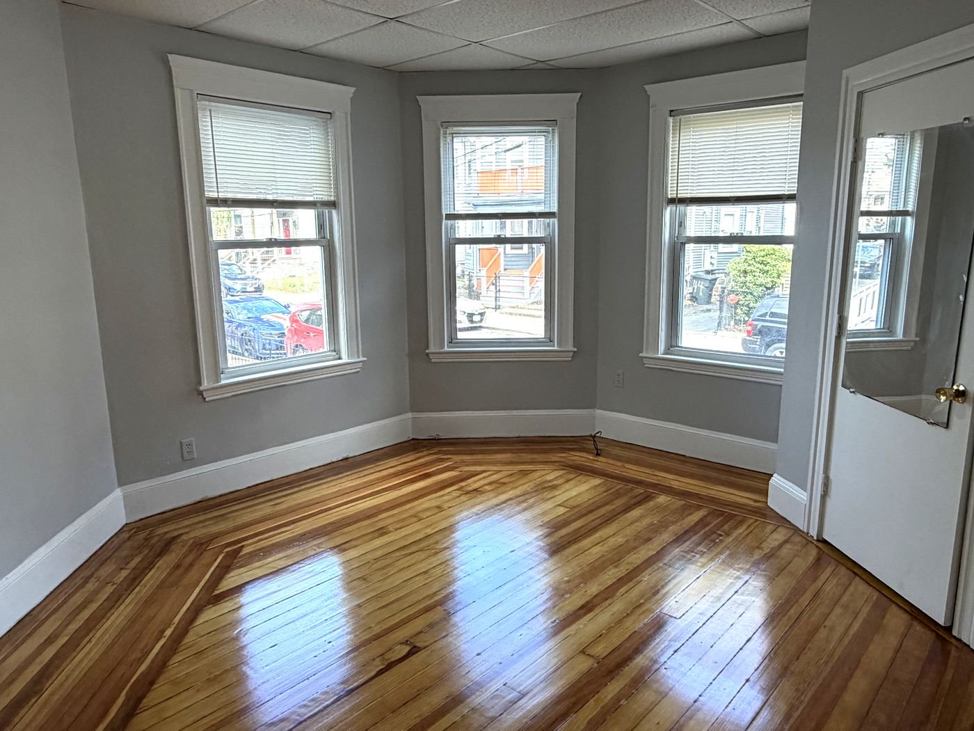 Front room with three windows and inlaid hardwood floors at 45 Wolcott Street